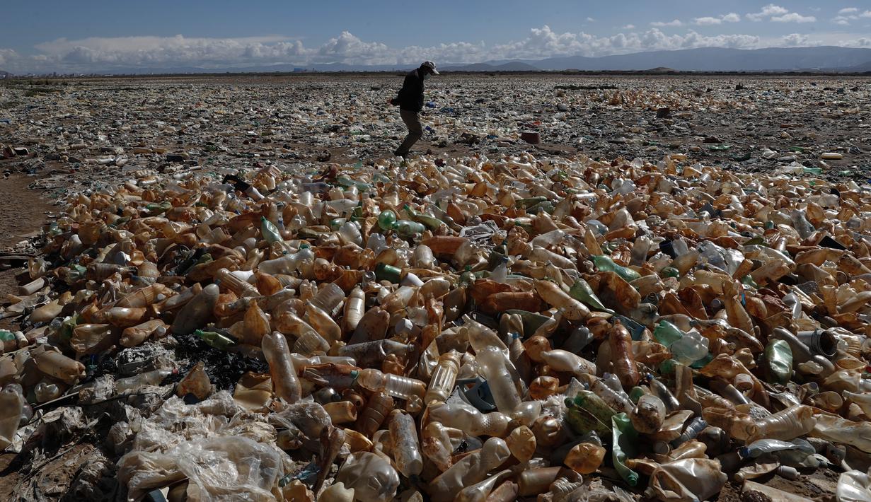 Seseorang berjalan di tengah botol plastik dan sampah di daerah kering Sungai Tagaret, yang mengalir ke Danau Uru Uru, dekat Oruro, Bolivia, Kamis (25/3/2021). Sungai ini mengalir ke Danau Uru Uru dengan membawa sampah-sampah yang mencemari danau. (AP Photo / Juan Karita)