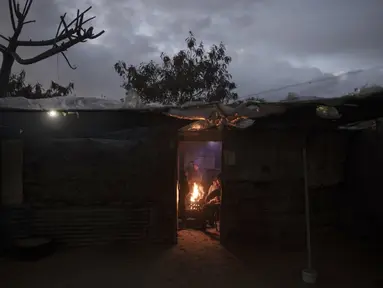 Sebuah keluarga Palestina menghangatkan diri di dekat api saat cuaca dingin di daerah kumuh di pinggiran kamp pengungsi Khan Younis, Jalur Gaza selatan pada Rabu, 19 Januari 2022. (AP Photo/Khalil Hamra)