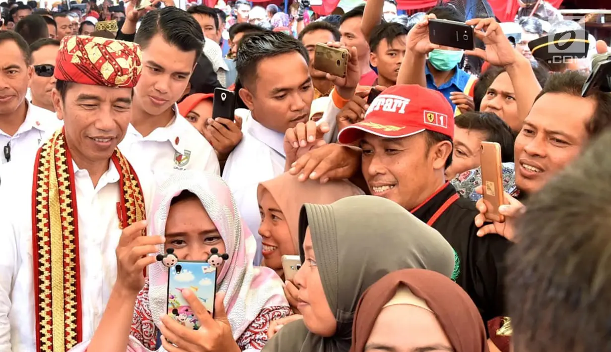 Warga berselfie dengan Presiden Joko Widodo saat acara penyerahan 1.300 sertifikat hak atas tanah untuk masyarakat di Kab Lampung Tengah, Jumat (23/11). Penyerahan sertifikat ini rangkaian kunjungan kerja Presiden ke Lampung. (Liputan6.com/HO/Biropers)