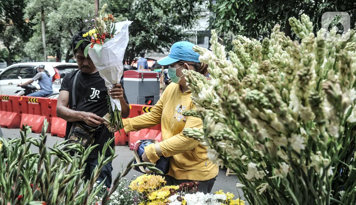 Pedagang bunga hias melayani pembeli di Pasar Petak Sembilan, Jakarta, Kamis (11/2/2021). Bunga hias yang dijual antara lain sedap malam, anggrek, krisan, dan lotus. (merdeka.com/Iqbal S. Nugroho)