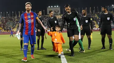 Bintang Barcelona Lionel Messi menggandeng bocah Afghanistan, Murtaza Ahmadi jelang laga melawan Al Ahli di Doha, Qatar, Selasa (13/12). Murtaza menjadi sensasi di internet karena mengenakan plastik dengan nomor punggung 10 untuk Messi. (Karim Jaafar/AFP)