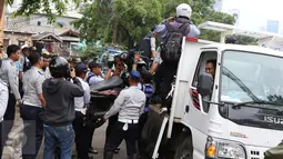 Petugas Dishub mengangkut motor ke atas truk saat razia parkir liar di kawasan Tanah Abang, Jakarta, Senin (14/11). Meski sudah ditertibkan, pengendara masih tak menghiraukan peraturan tersebut yang mengakibatkan kemacetan. (Liputan6.com/Gempur M Surya)