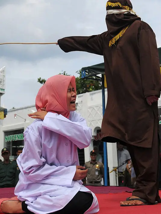 Nur Elita tampak meringis kesakitan saat petugas menyabetkan rotan ke punggungnya di halaman Masjid Baiturrahim, Ulee Lheue, Banda Aceh, Senin (28/12). Nur yang merupakan terpidana kasus khalwat mendapat hukuman 5 kali cambukan (AFP/dailymail.co.uk)