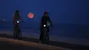 Dua orang pria bermain sepeda dengan latar belakang supermoon, di Lisbon, Portugal, Selasa (9/9/14). (REUTERS/Rafael Marchante)