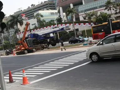 Sebuah mobil melintasi jalur khusus penyeberangan orang atau Pelican Crossing di kawasan MH Thamrin, Jakarta, Minggu (29/7). Pemasangan pelican crossing ini sebagai pengganti JPO di Bundaran HI yang akan dirobohkan. (Liputan6.cpm/Herman Zakharia)