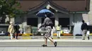 Seorang wanita mengenakan masker untuk mencegah penyebaran virus corona berjalan-jalan di taman di Tokyo (21/4/2021). Ibukota Jepang mengonfirmasi lebih dari 840 kasus virus corona baru pada hari Rabu. (AP Photo/Eugene Hoshiko)