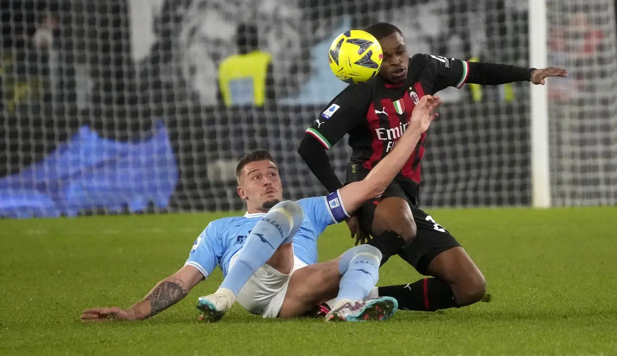 Bek AC Milan, Pierre Kalulu berebut bola dengan gelandang Lazio, Sergej Milinkovic-Savic selama pertandingan lanjutan Liga Serie A Italia di Stadion Olimpiade di Roma, Rabu (25/1/2023). Kekalahan membuat AC Milan tetap berada di peringkat kedua klasemen dengan 38 poin. (AP Photo/Gregorio Borgia)