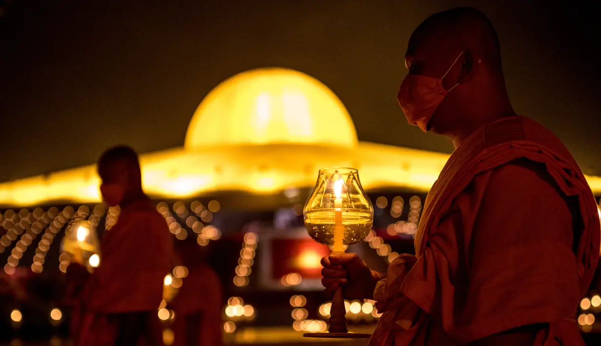 Biksu Buddha memegang lilin selama perayaan Makha Bucha di tengah pandemi COVID-19, di Wat Dhammakaya, utara Bangkok, Jumat (26/2/2021). Upacara keagamaan ini pun menjadi salah satu yang terbesar di Thailand karena banyaknya umat Buddha yang tinggal di wilayah Gajah Putih. (Jack TAYLOR/AFP)