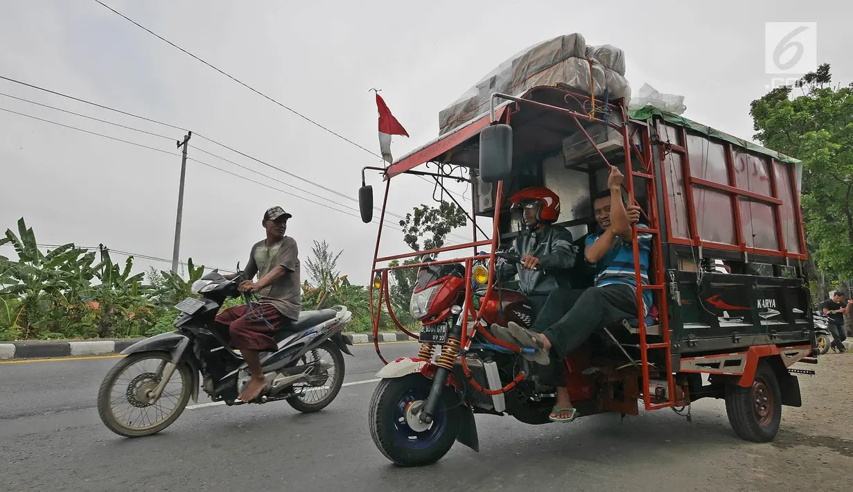 Pemudik bersama keluarganya menggunakan motor bak roda tiga bersiap kembali melakukan perjalanan mudik di Jalur Pantura kawasan Pemalang, Jawa Tengah, Senin (3/6/2019). Keluarga ini sudah sejak tiga tahun lalu menggunakan motor bak roda tiga untuk mudik. (Liputan6.com/Herman Zakharia)