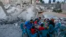 Sebuah keluarga Palestina berbuka puasa di sebelah rumah mereka yang hancur selama eskalasi dua hari, di Rafah, Jalur Gaza selatan (8/5/2019). Perang yang terjadi antara Gaza dan Israel masih berlangsung hingga detik ini. (AFP Photo/Said Khatib)