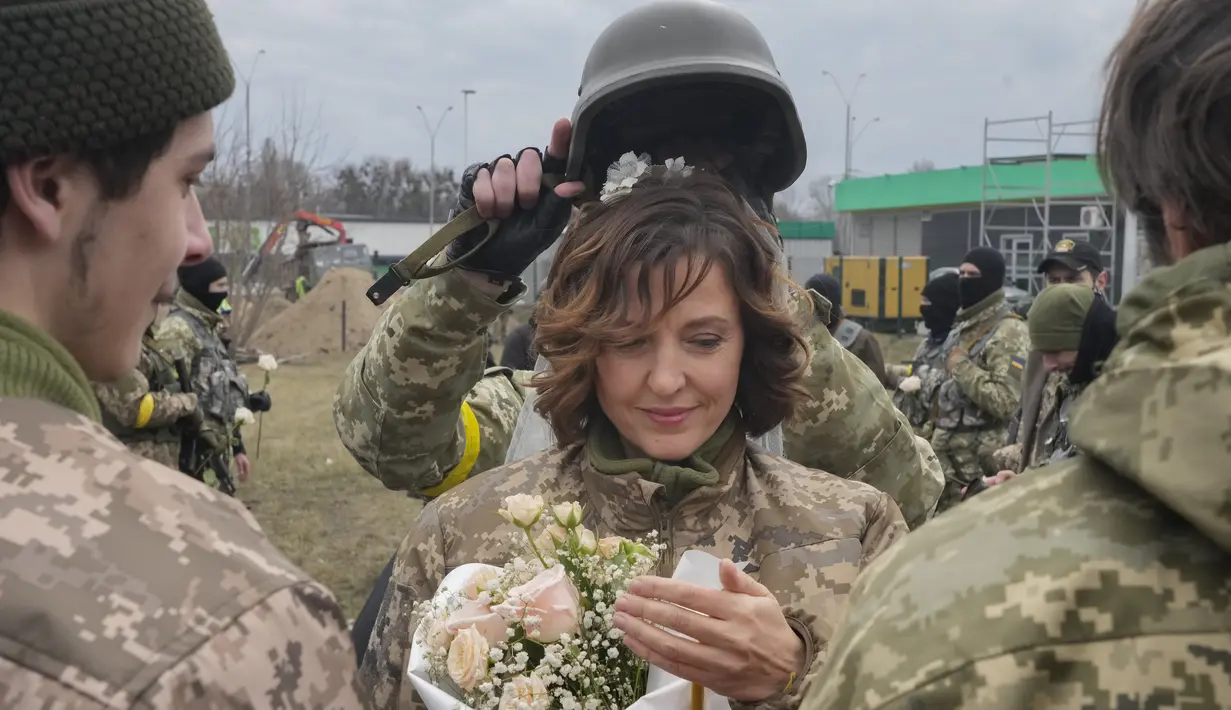 Seorang tentara memegang helm sebagai tiara mahkota pada upacara pernikahan anggota Pasukan Pertahanan Teritorial Ukraina Lesia Ivashchenko dan Valerii Fylymonov di pos pemeriksaan di Kiev, 6 Maret 2022. Kedunya menikah dengan upacara seadanya yang dilakukan korps mereka. (AP/Efrem Lukatsky)