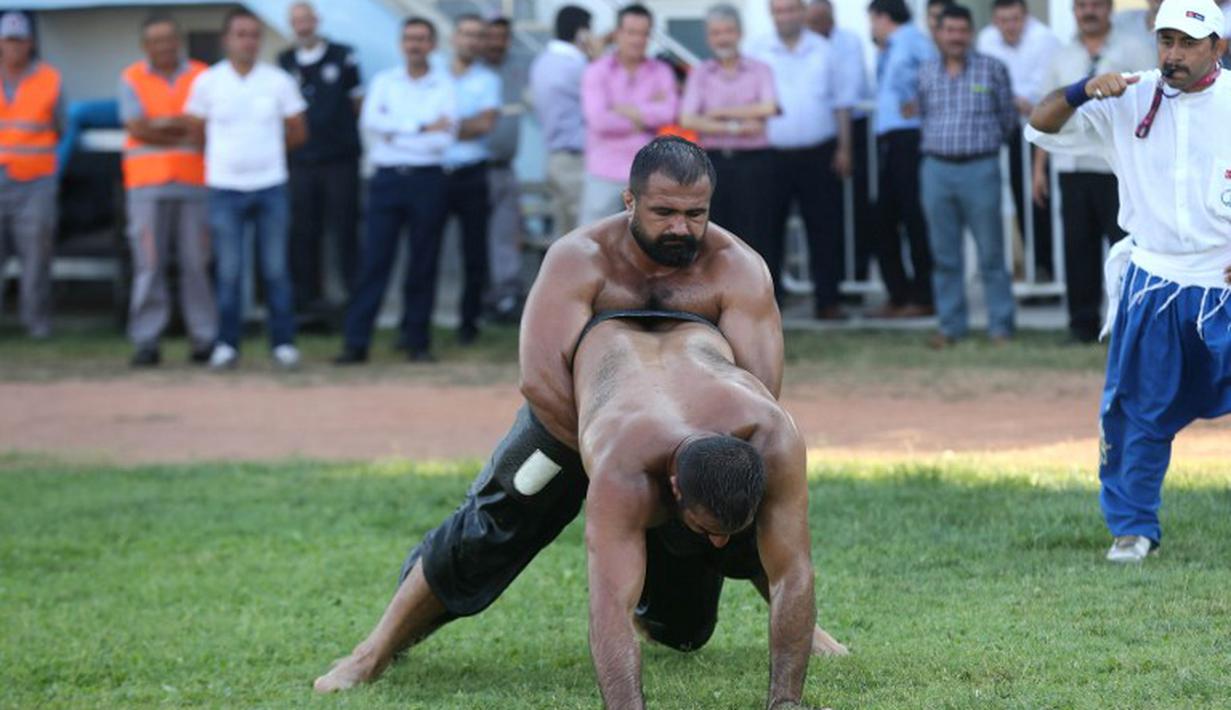 Pertandingan gulat oli ini di pimpin oleh seorang wasit. (AFP Photo/Adem Altan)