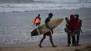 Peselancar memegang papan selancar saat berlibur Lebaran di Pantai Lhoknga, Aceh Besar, Aceh, Minggu (9/6/2019). (CHAIDEER MAHYUDDIN/AFP)