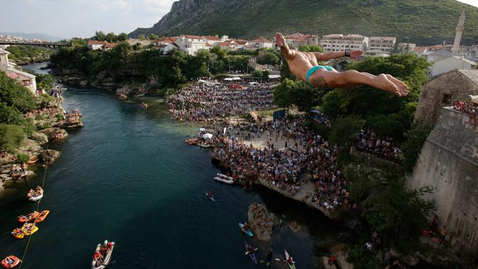 Peserta melompat dari Jembatan Old Mostar pada kompetisi menyelam tradisional ke-452 di Mostar, Bosnia, 29 Juli 2018. Penyelam berlari sebelum melompat dari jembatan, jatuh ke sungai dan terbang di udara seperti burung melakukan trik. (AP/Amel Emric)