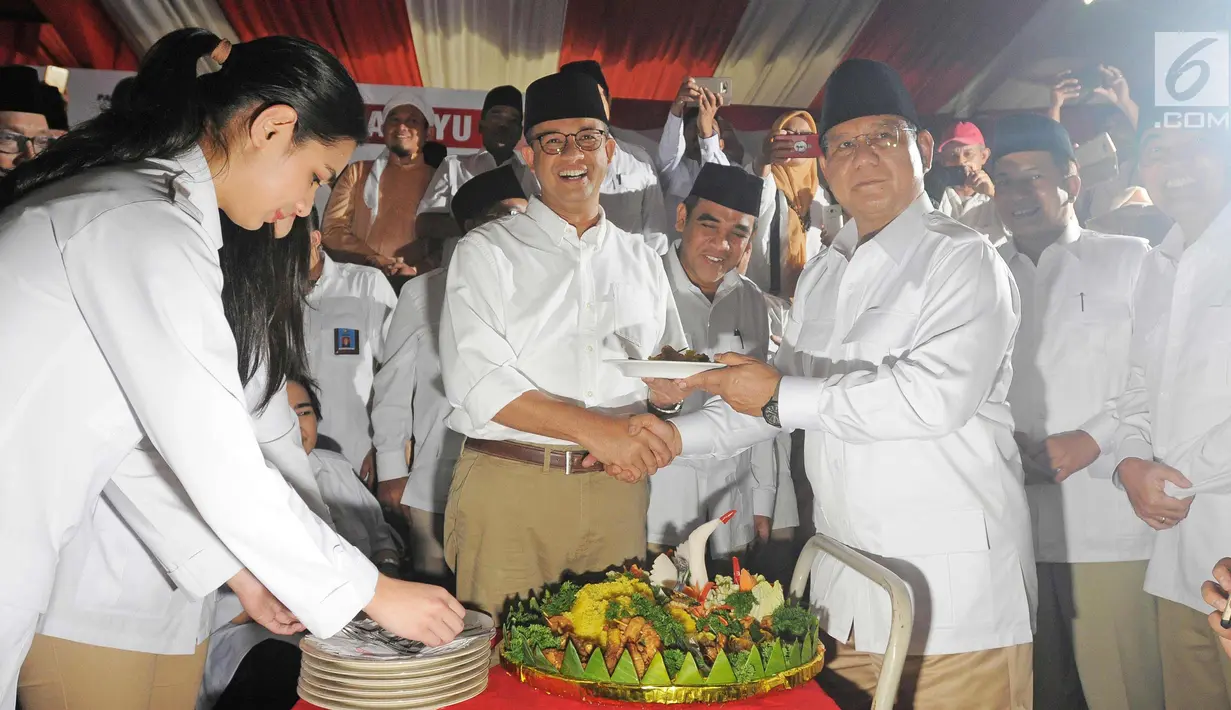 Ketua Dewan Pembina Partai Gerindra, Prabowo Subianto memberikan potongan tumpeng ke Gubernur DKI Jakarta, Anies Baswedan dalam Hari Ulang Tahun ke-10 Tahun yang digelar di kantor DPP Partai Gerindra, Jakarta, Sabtu (10/2). (Liputan6.com/Herman Zakharia)