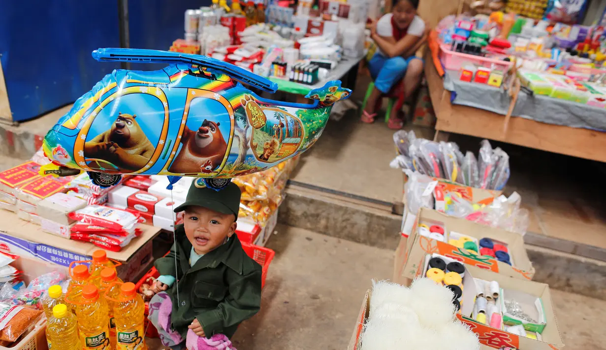 Seorang anak memakai baju mirip seragam Tentara Negara Persatuan WA i pasar Mongmao, wilayah pemberontak Wa di Myanmar, 1 Oktober 2016. (REUTERS/Soe Zeya Tun)