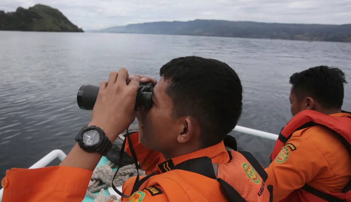Tim SAR menggunakan teropong saat proses pencarian korban KM Sinar Bangun yang tenggelam di Danau Toba, Sumatra Utara, Rabu (20/6). Hingga hari ketiga, sebanyak 18 penumpang selamat, dua tewas dan 160 lainnya dalam proses pencarian. (AP/Binsar Bakkara)