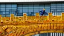 Seorang pekerja menyelesaikan pembangunan 'Golden Bridge Silk Road' di Beijing, China (18/4). Ada 28 kepala negara dan kepala pemerintahan yang akan menghadiri pertemuan yang digagas Presiden China Xi Jinping tersebut. (AP Photo/Andy Wong)