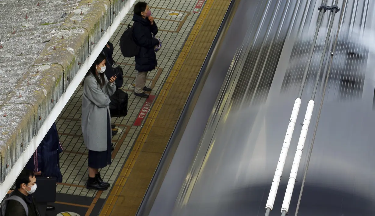 Penumpang mengenakan masker untuk mencegah penyebaran virus corona menunggu kereta di stasiun di Tokyo (8/2/2021).  Jumlah infeksi virus corona di Ibu Kota Tokyo, Jepang, meningkat sampai sembilan kali lipat sejak akhir musim panas lalu. (AP Photo/Eugene Hoshiko)