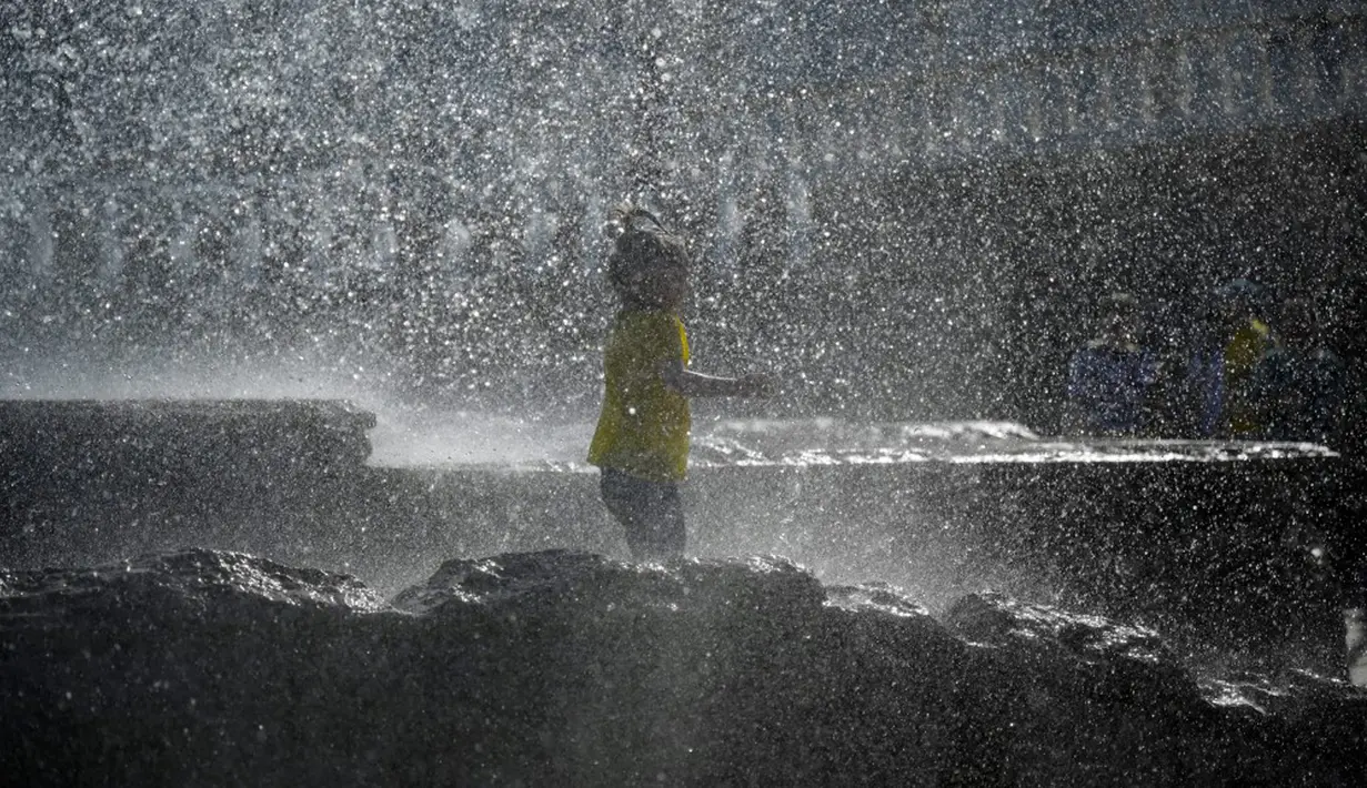 Seorang anak mendinginkan diri di air mancur musim semi yang panas di Moskow, Rusia, Selasa (18/5/2021). Suhu di Moskow telah mencapai 31 derajat Celcius. (Natalia KOLESNIKOVA/AFP)