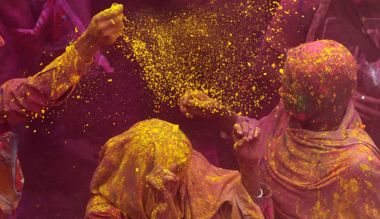 Janda India menaburkan bubuk berwarna-warni saat mengikuti perayaan Holi di kota Vrindavan, India, (9/3). Holi dirayakan di negara India, Nepal, Bangladesh, dan negara dengan pemeluk agama Hindu. (AFP Photo / Dominique Faget)