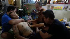 Seorang biksu Budha saat menato seorang pria menggunakan jarum tradisional di Wat Bang Phra, Nakhon Pathom, Thailand , (18/3). Setiap tahun saat musim semi, ribuan orang datang ketempat ini untuk menato tubuhnya. (REUTERS / Chaiwat Subprasom)
