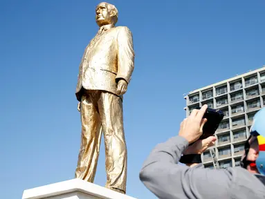 Warga mengabadikan patung emas raksasa PM Israel Benjamin Netanyahu di tengah-tengah Rabin Square, Tel Aviv, Selasa (6/12). Patung PM Israel ini telah menghebohkan seluruh warga setelah tiba-tiba muncul misterius sejak tadi malam. (REUTERS / Baz Ratner)
