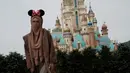 Seorang pengunjung yang mengenakan masker berpose untuk foto di Disneyland Hong Kong pada Jumat (25/9/2020). Setelah dibuka dan tutup kembali, Disneyland Hong Kong dibuka kembali untuk wisatawan. (AP Photo/Kin Cheung)