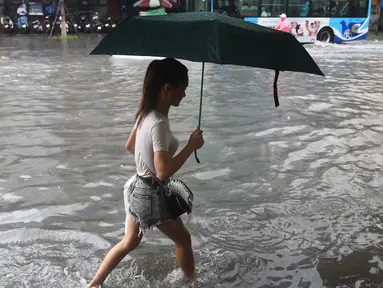 Seorang wanita melintasi banjir setelah badai tropis Talas terjadi di Hanoi, Vietnam utara (17/7). Menurut Direktur Pusat Peramalan Nasional Hidro-Meteorologi Badai Talas diprediksi akan melanda provinsi-provinsi utama Vietnam. (AFP Photo/Hoang Dinh Nam)