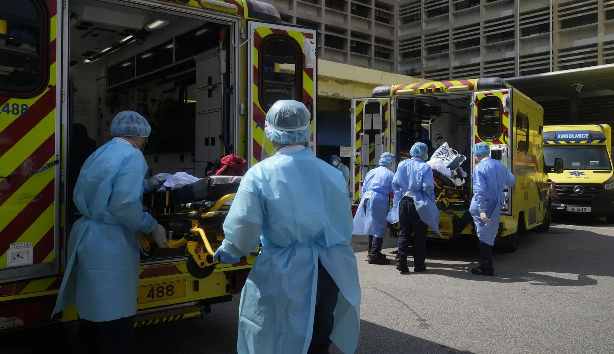 Pekerja medis yang mengenakan pakaian pelindung memindahkan pasien dari ambulans ke rumah sakit di Hong Kong, Jumat (4/3/2022). Pemimpin Hong Kong awal pekan ini mengatakan mobilitas orang mungkin dibatasi selama tes covid-19 massal wajib ketika kasus harian mencapai rekor. (AP Photo/Kin Cheung)