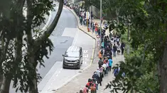 Orang-orang mengantre di stasiun pengumpulan spesimen bergerak untuk pengujian Covid-19 di distrik Tung Chung, Hong Kong pada 10 Februari 2022. Antrean terjadi ketika pihak berwenang bergegas untuk meningkatkan kapasitas pengujian menyusul rekor jumlah infeksi baru yang tinggi. (Peter PARKS / AFP)