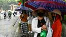 Para penumpang menunggu di halte bus selama hujan lebat di Hanoi (14/10/2020). Badai tropis Nangka menghantam Vietnam tengah-utara yang mengakibatkan bencana alam, terutama hujan lebat dan banjir, telah menyebabkan 28 orang tewas dan 12 lainnya hilang. (AFP Photo/Manan Vatsyayana)