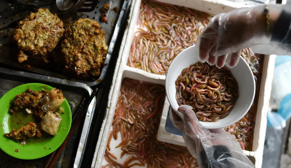 Pedagang membuat kuliner cha ruoi di sebuah warung di Hanoi, Vietnam, Jumat (14/12). Cha ruoi merupakan kue hangat berbentuk dadar yang terbuat dari campuran daging babi, telur, daun dill, kulit jeruk, dan segenggam cacing goreng. (Manan Vatsyayana/AFP)