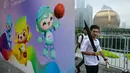 Orang-orang berjalan melewati poster Asian Games 2022 di sepanjang jalur pejalan kaki sungai Qiantang di Hangzhou, provinsi Zhejiang, China pada 22 September 2023. (MANAN VATSYAYANA/AFP)