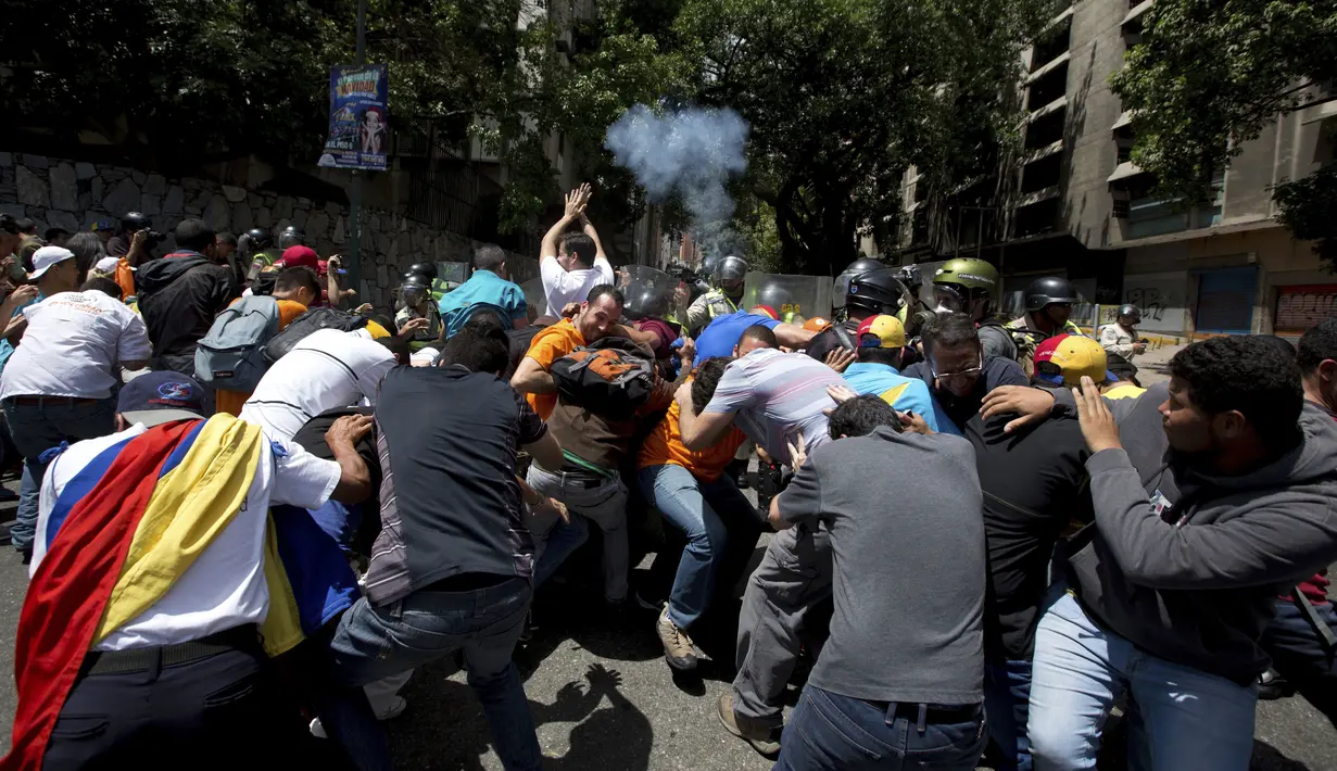Polisi menembakkan gas air mata saat aksi menolak keputusan Mahkamah Agung  yang mencabut kekuasaan dari Majelis Nasional di Caracas, Venezuela, Sabtu (1/4). MA akhirnya membatalkan putusannya untuk memakzulkan kongres. (AP Photo / Fernando Llano)