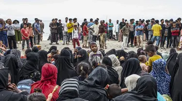 Pengungsi Rohingya duduk bersama di tanah setelah mereka tiba dengan perahu di Pantai Kalee, Laweung, Kabupaten Pidie, Provinsi Aceh, Indonesia, Selasa (14/11/2023). Hampir 200 pengungsi Rohingya, termasuk banyak perempuan dan anak-anak, terdampar di provinsi paling barat Indonesia pada 14 November, menurut laporan setempat. (Jon S./AFP)