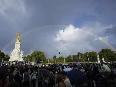 Orang-orang berkumpul di luar Istana Buckingham saat pelangi ganda muncul di atas langit London, Kamis, 8 September 2022. Di hari wafatnya  Ratu Elizabeth II, pelangi rupanya muncul di langit Istana Buckingham. Tidak hanya satu pelangi, tapi dua. (AP Photo/Frank Augstein)