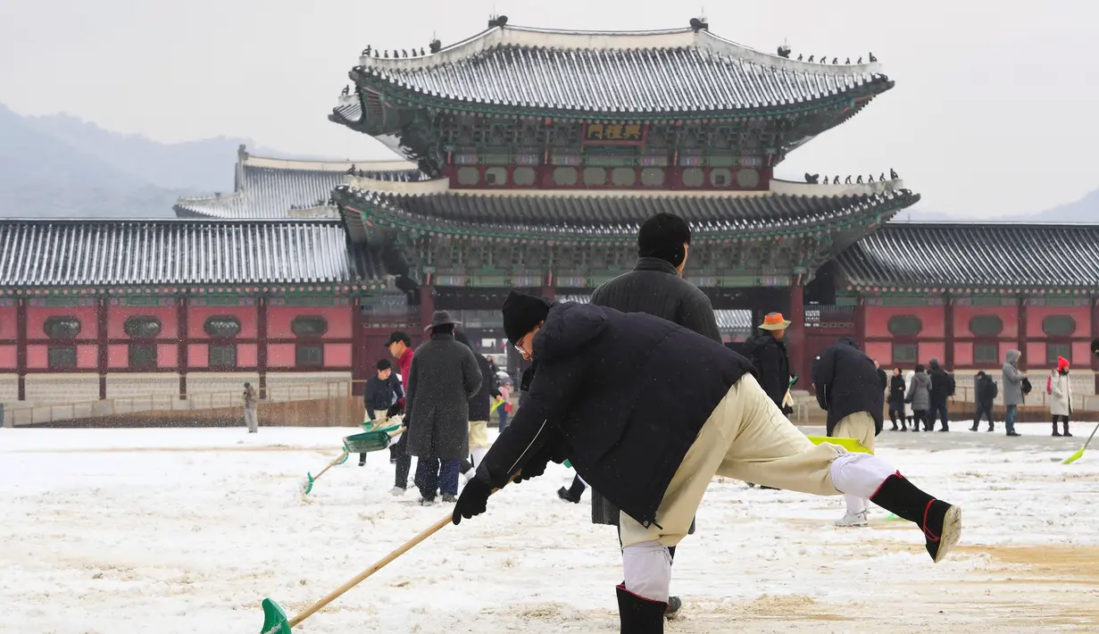 Pekerja membersihkan salju di istana Gyeongbokgung setelah salju turun Seoul, Korea Selatan (15/2). Istana ini hancur pada saat invasi Jepang ke Korea tahun 1592-1598dan dibangun lagi selama tahun 1860-an. (AFP Photo/Jung Yeon-je)