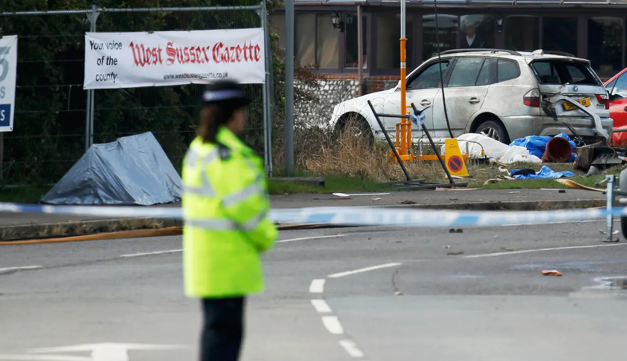 Petugas berdiri di dekat lokasi jatuhnya jet Hawker Hunter di Jalan Raya A27, Shoreham, Inggris, Minggu (23/8/2015). Pesawat yang tengah mengikuti Shoreham Airshow tersebut menabrak sejumlah mobil dan menewaskan  tujuh orang. (REUTERS/Luke MacGregor)