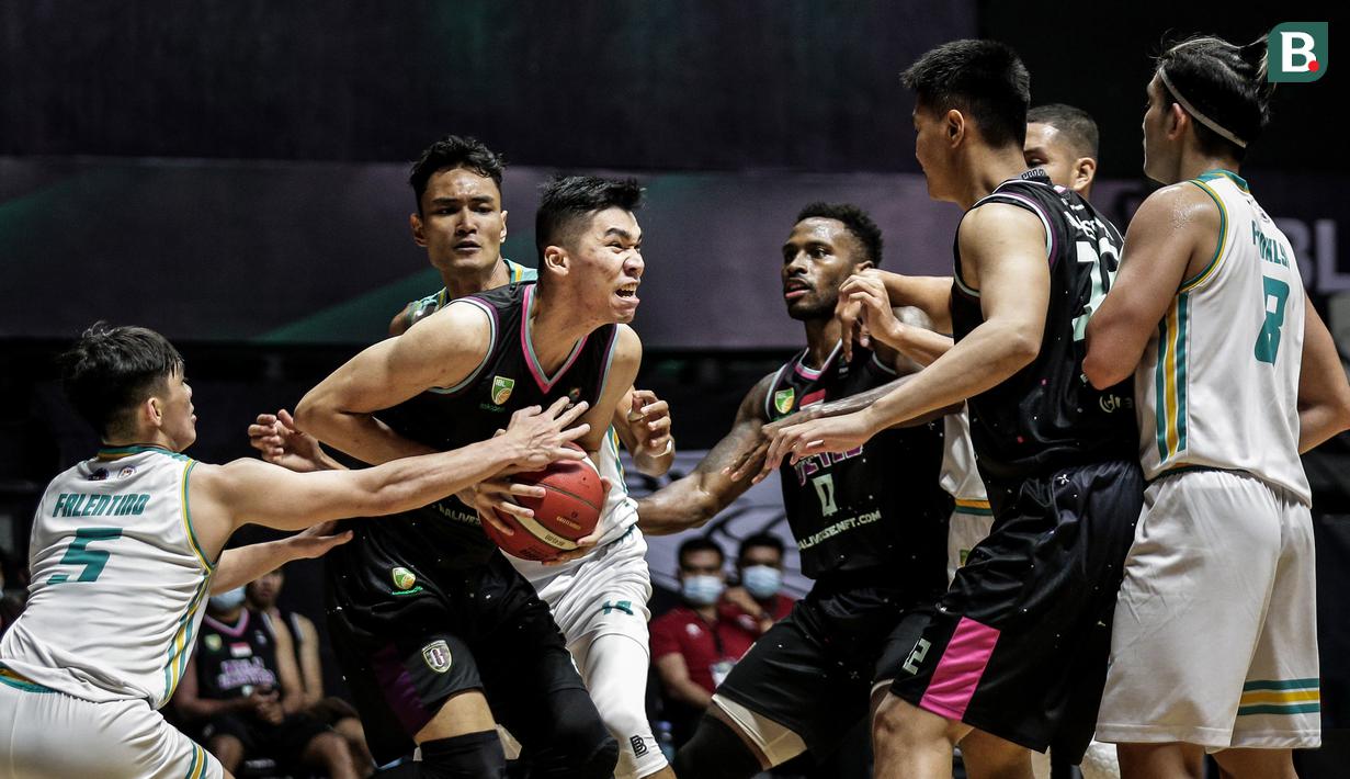 Pemain Bali United Basketball, Lutfi Alfian Eka Koswara (dua kiri) berebut bola dengan pemain Satya Wacana Salatiga saat laga lanjutan Seri 1 IBL 2022 di Hall Basket GBK, Senayan, Kamis (20/01/2022). (Bola.com/Bagaskara Lazuardi)