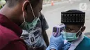 Petugas memeriksa suhu tubuh seorang anak saat akan memasuki Kompleks Istana Kepresidenan, Jakarta, Selasa (3/3/2020). Istana Kepresidenan memperketat pemeriksaan terhadap tamu, ASN, dan pejabat negara untuk mencegah penyebaran virus corona (COVID-19). (Liputan6.com/Faizal Fanani)