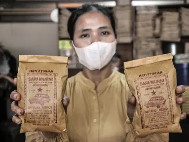 Pekerja menunjukkan kopi yang siap dipasarkan di toko kopi Sari Murni, Jatinegara, Jakarta Timur, Selasa (4/1/2021). Toko kopi yang berdiri sejak tahun 1952 ini juga dikenal dengan Kopi Cap Sedan. (merdeka.com/Iqbal S. Nugroho)