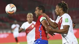 Bek Chile, Jean Beausejour dan gelandang Peru, André Carrillo berebut bola dalam laga Kualifikasi Piala Dunia 2022 zona Conmebol di Estadio Nacional, Santiago, Jumat (13/11/2020). Chile mengalahkan Peru 2-0 berkat gol yang diborong Arturo Vidal. (Martin Bernetti, Pool via AP)