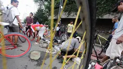 Seorang teknisi sepeda sedang memperbaiki roda sepeda salah seorang pengunjung  di kawasan Bundaran Hotel Indonesia, Jakarta, Minggu (14/12/2014). (Liputan6.com/Faizal Fanani)