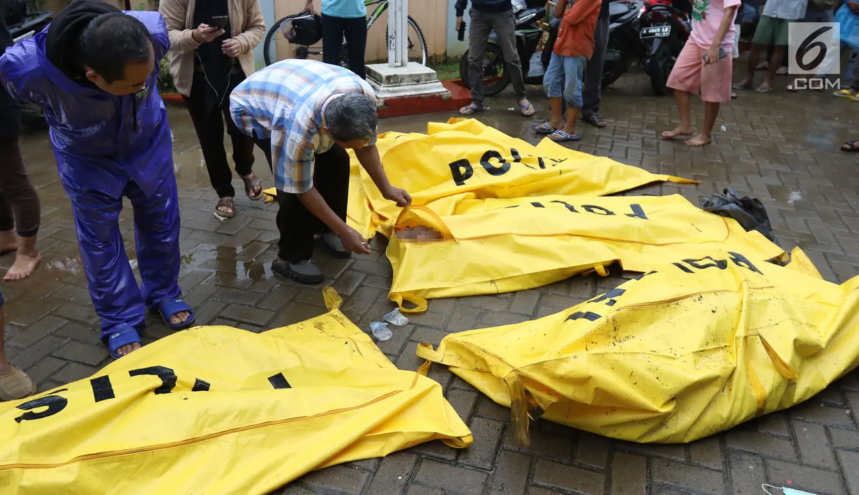 Warga melihat jenazah korban gelombang Tsunami Anyer di Puskesmas Carita, Banten, Minggu (23/12). Tim SAR masih melakukan pencarian jenazah yang sebagian besar berasal dari Pantai Carita. (Liputan6.com/Angga Yuniar)