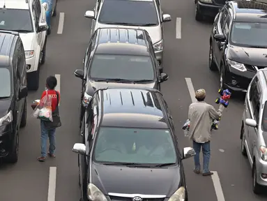 Pedagang asongan menjajakan dagangannya di tengah kemacetan kawasan Harmoni, Jakarta, Selasa (19/4). Kemacetan yang semakin parah di Ibukota menjadi keuntungan tersendiri bagi para pedagang asongan untuk mencari nafkah. (Liputan6.com/Immanuel Antonius)