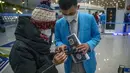 Pekerja membantu pelancong mengisi status kesehatan elektronik COVID-19 mereka di area kedatangan internasional di Bandara Internasional Beijing, China (9/1/2023). Pelancong internasional pertama tiba di China tanpa karantina wajib yang telah diberlakukan pada awal penerbangan. Pandemi tiga tahun lalu setelah pembatasan dicabut mulai hari Minggu. (AP/Mark Schiefelbein)