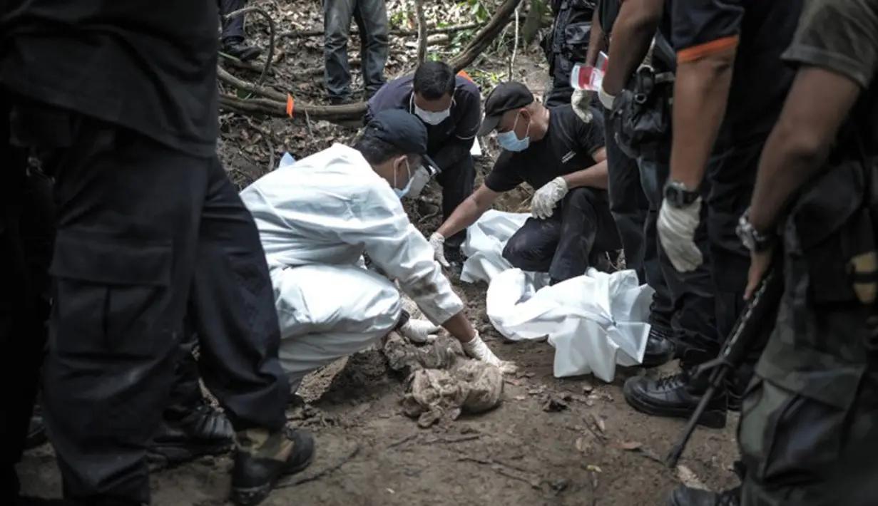 Tim forensik Malaysia memeriksa tubuh manusia yang baru digali dari sebuah makam tak bertanda di Bukit Wang Burma, dekat perbatasan Malaysia-Thailand, (26/5/2015). 139 kuburan massal yang berisi kerangka orang ditemukan.  (AFP PHOTO/MOHD RASFAN)