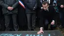 Presiden Prancis Emmanuel Macron meletakkan batu di atas makam Yahudi yang dicoret simbol Nazi di pemakaman Yahudi, Quatzenheim, Prancis, Selasa (19/2). Macron juga juga menyatakan akan menghukum para pelaku vandalisme. (Frederick FLORIN/AFP)