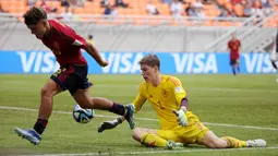 Kiper&nbsp;Timnas Jerman U-17, Max Schmitt (kanan), berhasil menahan tendangan pemain Spanyol U-17, Juan Hernandez saat pertandingan perempat final Piala Dunia U-17 2023 yang berlangsung di Jakarta International Stadium, Jumat (24/11/2023). (Bola.com/M Iqbal Ichsan)